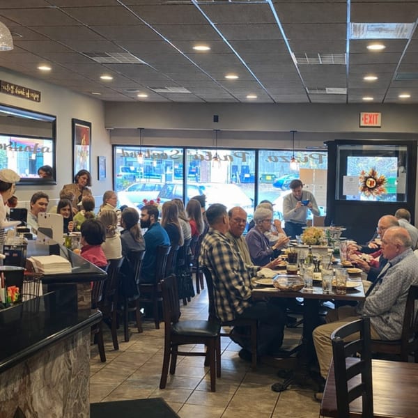 Diners seated at tables in a restaurant with large windows and an "EXIT" sign.